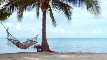 Relaxed woman lying in hammock on the beach - Powered by Adobe