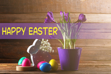 Easter greeting card. Colorful eggs with crocus flowers on wooden background