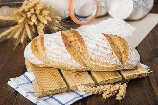 Pan de masa madre natural hecho a mano por un panadero tradicional decorado con espigas de trigo y centeno