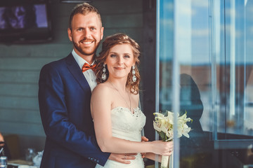 Closeup portrait of stylish young bride and groom posing on street at sunny day