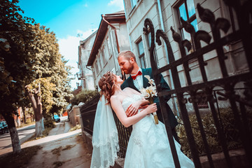 Obraz premium Closeup portrait of stylish young bride and groom posing on street at sunny day