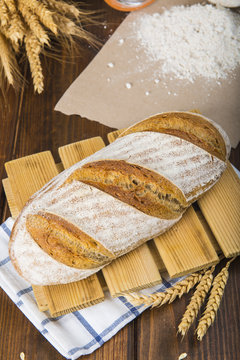 Pan de masa madre natural hecho a mano por un panadero tradicional decorado con espigas de trigo y centeno