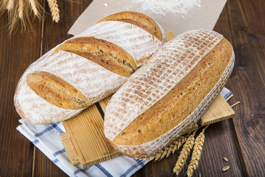 Pan de masa madre natural hecho a mano por un panadero tradicional decorado con espigas de trigo y centeno