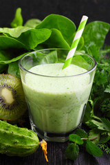 A glass of smoothie with green vegetables and spinach
