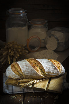 Pan de masa madre natural hecho a mano por un panadero tradicional decorado con espigas de trigo y centeno