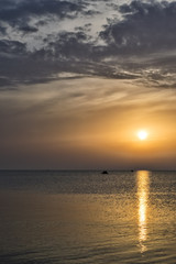 Sunset on the sea, the solar path, the people in the boat on the