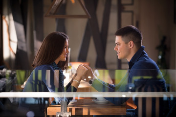 Happy young couple in love holding hands and looking at each other while having a romantic dinner at the restaurant