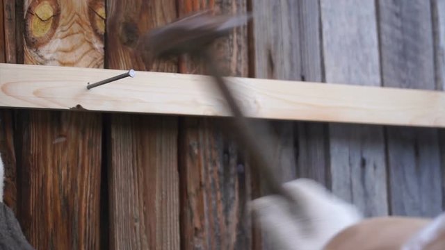 footage man hammers a nail into a plank.