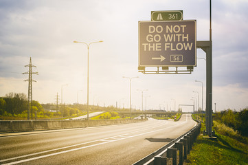 Traffic sign with text Do Not Go With The Flow. Appeal to noncoformism. Sunny positive atmosphere