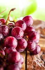Red grapes branch wiht green leaves on old rustic wooden table