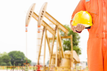 engineer hand holding yellow helmet for workers against background oil and gas process