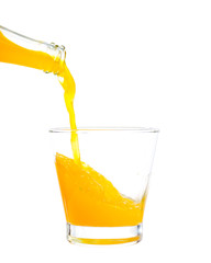 Pouring orange juice on a glass on white background