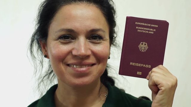 Closeup portrait shot of a happy middle aged woman with a German passport ID which is needed to go on vacation or take business trips outside of Germany and the EU to other countries of the world.