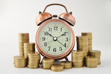 coins stack and alarm clock on white background