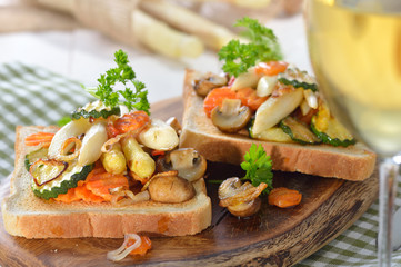 Veganer Toast mit gebratenem weißen Spargel und weiterem Gemüse, mit einem Glas Weißwein serviert - Vegan toast with fried white asparagus and other mixed vegetables, served with a glass of white wine