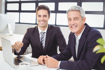 Portrait of smiling business people with laptop 
