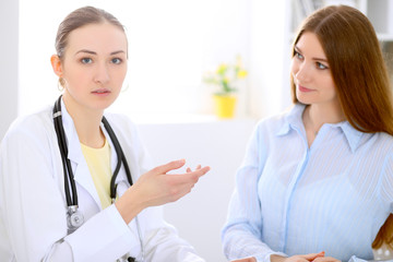 Fototapeta premium Doctor and patient sitting at the desk near window, sun shines