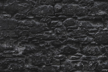 Dark brown old medieval natural stone wall. Texture, background or wallpaper.