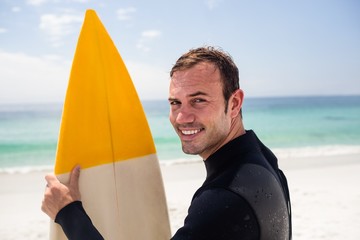 Happy man holding a surfboard on the beach