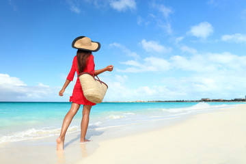 Beachwear woman tourist with straw sun hat and beach bag walking on tropical summer vacation...