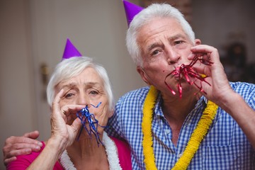 Portrait of senior couple blowing party horn 