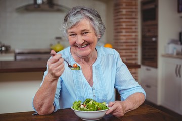 Smiling senior woman having vegetable salad 