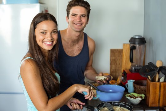 Happy young couple cooking food in kitchen