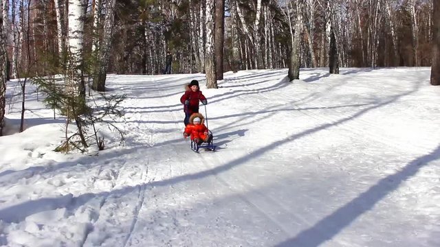 children sledding down a snowy hill