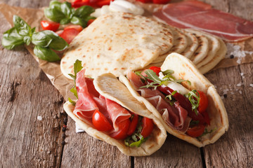 Tasty Italian piadina stuffed with ham, cheese and vegetables close-up. Horizontal
