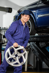 Fototapeta na wymiar Happy Mechanic Holding Alloy At Repair Shop