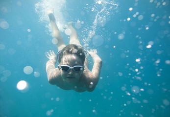 Fototapeta na wymiar The boy in the sea swimming under water