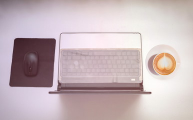 Computer notebook and a cup of coffee on white background with gradient filter.Top view