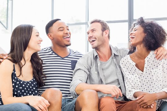 Friends Sitting On Sofa And Laughing