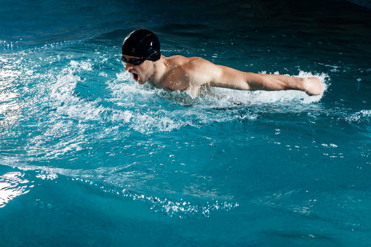 Muscular young man swims the butterfly