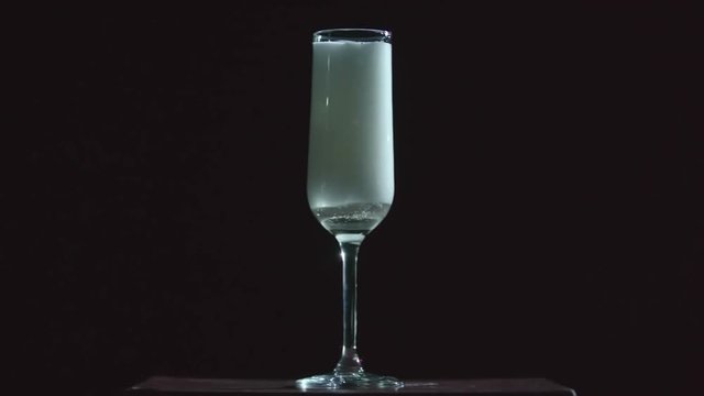 Close up of pouring champagne into the flute on dark background