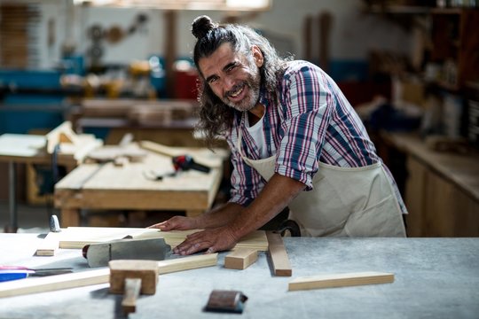 Male carpenter measuring wooden plank