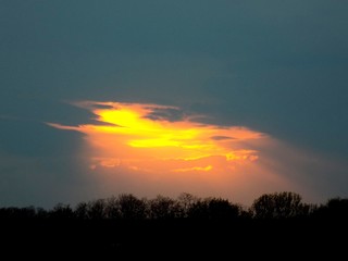 Sunlight beaming during sunset through a hole in the clouds