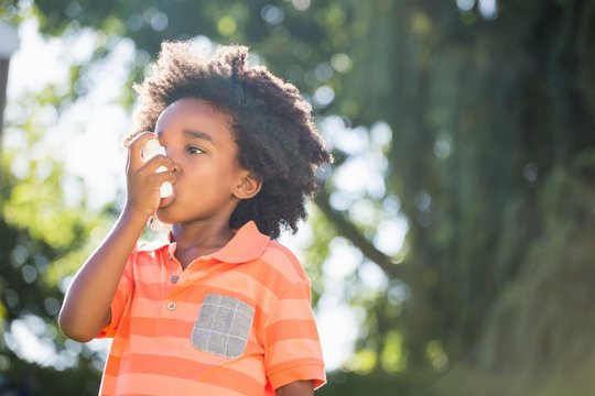 Cute mixed-race boy using a asthmatic spray