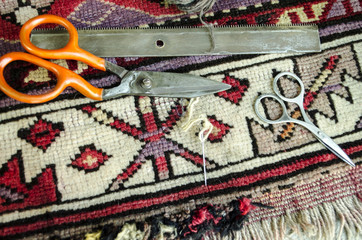 Worn old woolen carpet with scissors,a comb with needle and thread