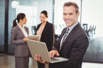 Portrait of businessman holding laptop in the office