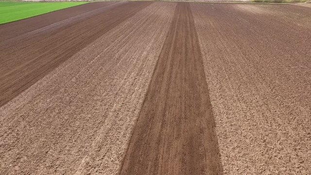 Tractor cultivating arable land for seeding crops, aerial view