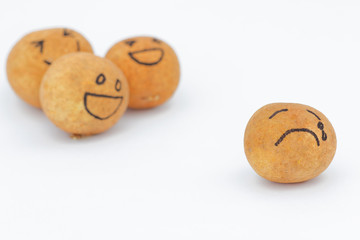 A group of brown ball laughing in the background while the brown ball in front alone and look sad and depressed. Concept of discrimination,bully,mental illness.
