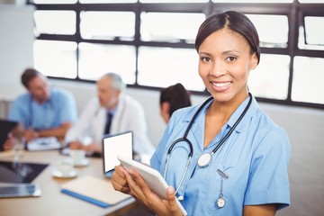 Happy female doctor using digital tablet in conference room
