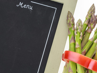 Bunch of asparagus tied with pepper ring and blank chalkboard menu closeup