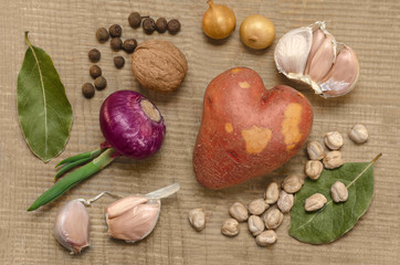Raw potatoes and spices, on the old wooden surface.
