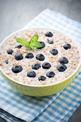 Buckwheat porridge in a bowl with mint leaves and blueberries.