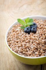 Buckwheat porridge in a bowl with mint leaves and blueberries.