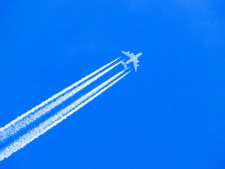 Airplane with chemtrails on blue sky