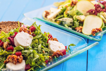 fresh mix vegetable salads on glass plate on blue wooden background, product photography for restaurant or healthy lifestyle