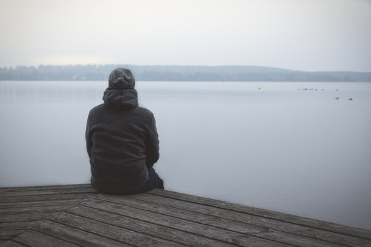 Einsamer Mann sitzt auf Steg am See oder Fluss / Lonesome Huy At The Lake